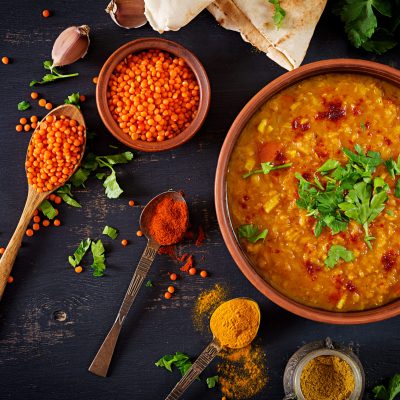 Indian dal. Food. Traditional Indian soup lentils.  Indian Dhal spicy curry in bowl, spices, herbs, rustic black wooden background. Top view. Authentic Indian dish. Overhead. Flat lay